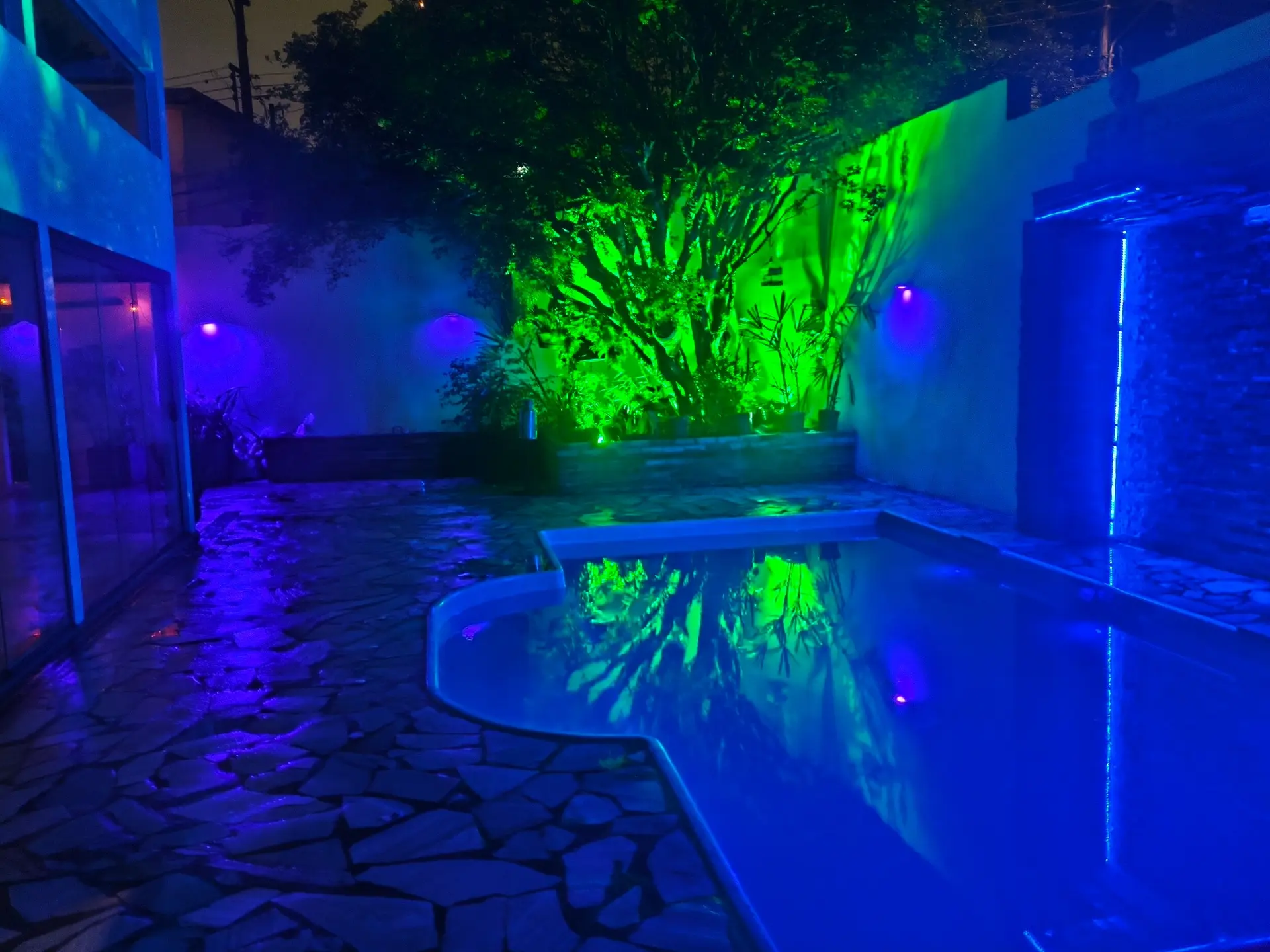 Piscina e área de lazer da Casa Góes iluminadas à noite