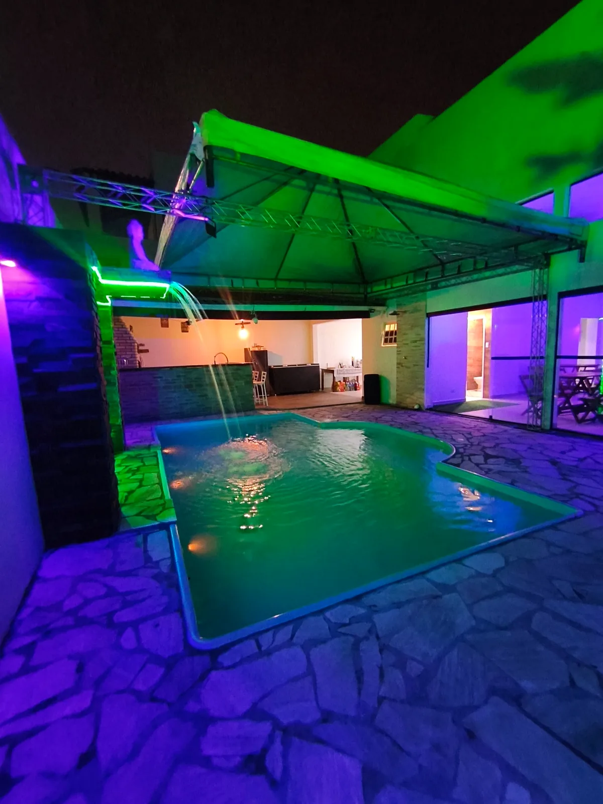 Piscina iluminada e área coberta da Casa Góes